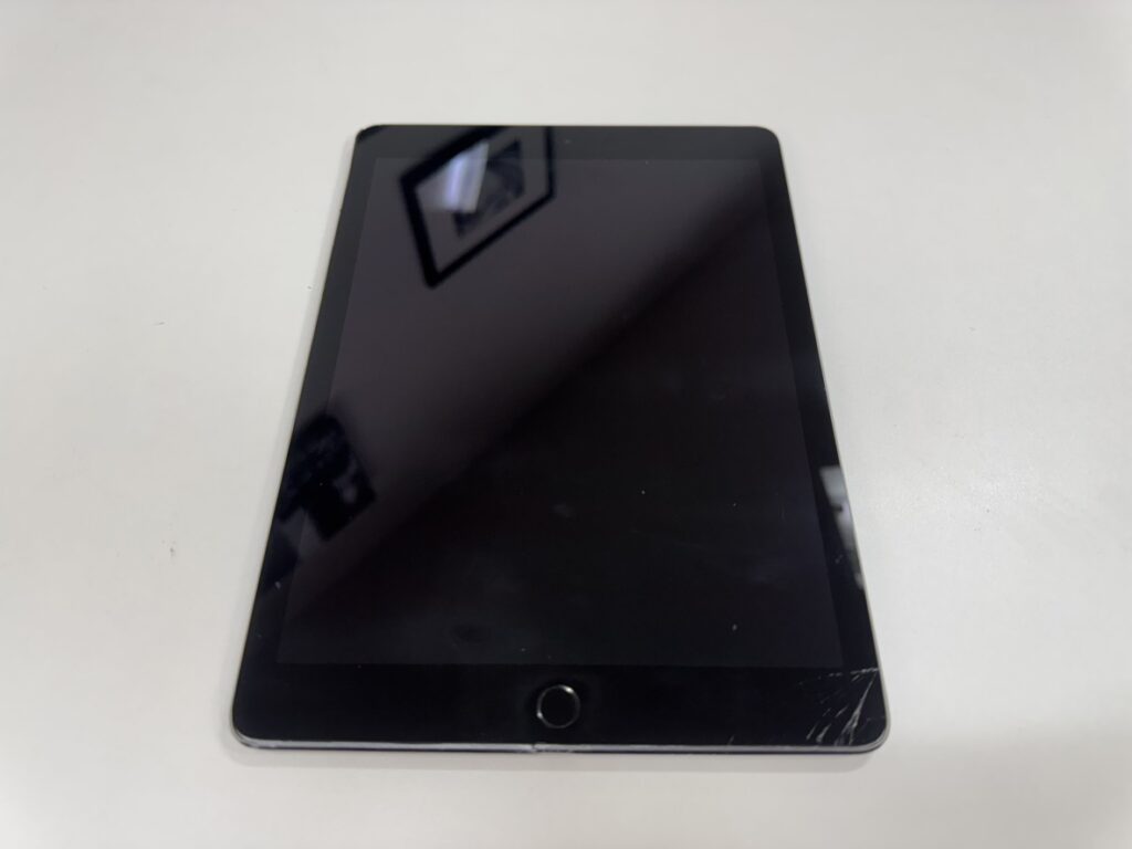 iPad Air 2 の画面右下が衝撃で大きく割れた状態。法人で業務利用されている端末で、表示は問題ないがタッチ操作に乱れが見られる修理前の状態を撮影した写真