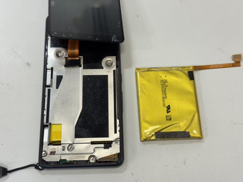 横浜関内でarrows We3のバッテリー交換を行うため、画面を開き基板カバーを取り外している修理工程