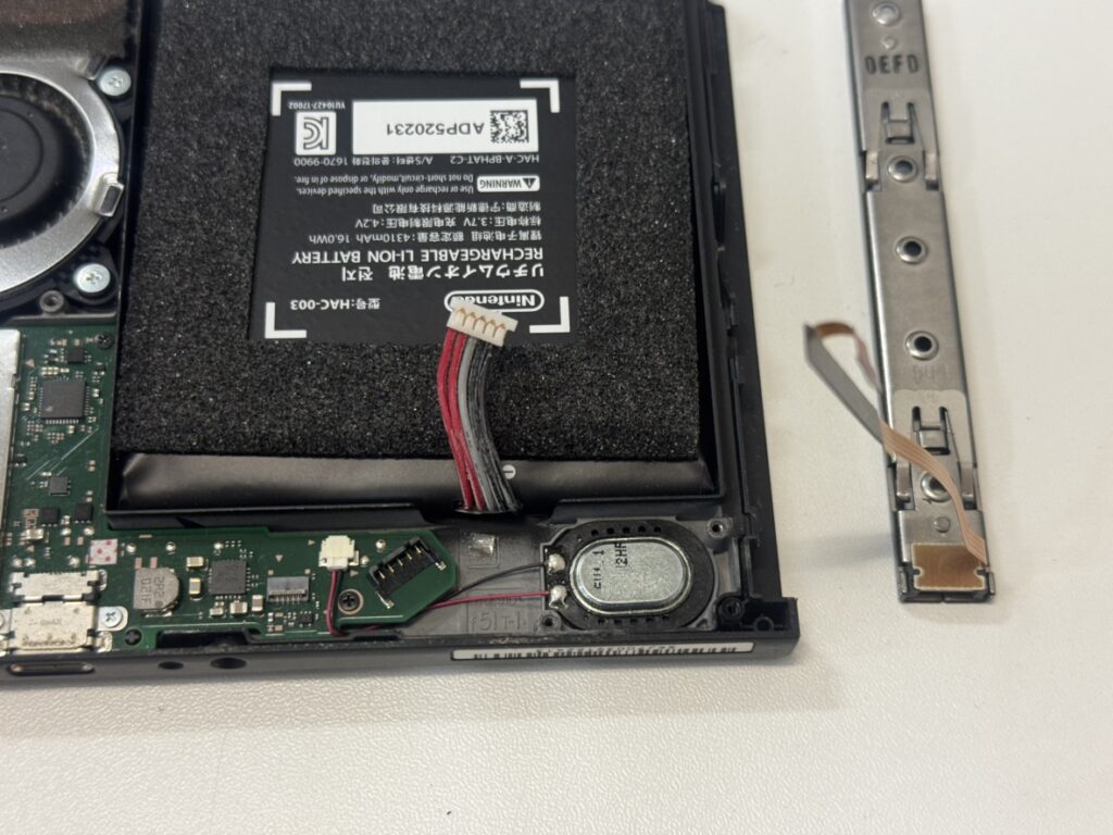 Nintendo Switchを分解し反応しなくなった古い左レールを基板から取り外している作業風景