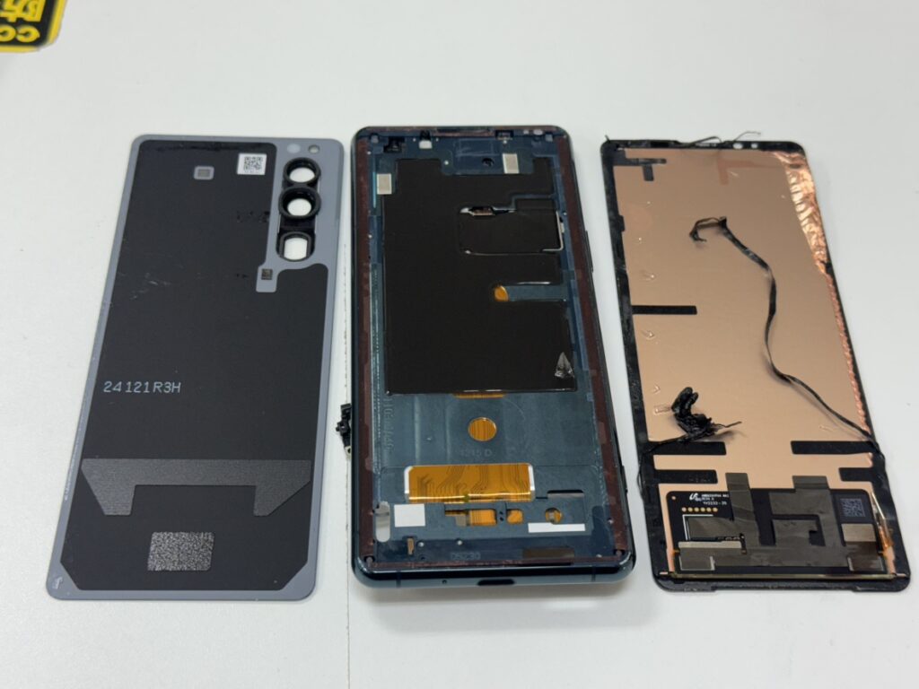 Xperia 5 IIIの背面を開き、基板から液晶パネルのコネクタを外している修理風景。