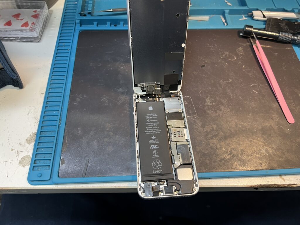 iPhone SE 初代の内部基板を傷つけないよう慎重に分解する様子