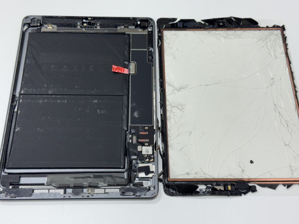 iPad 第9世代の割れたガラスを慎重に剥がし、内部の清掃を行っている修理風景。