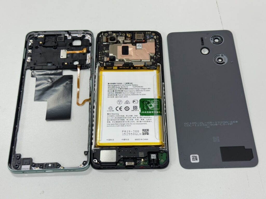OPPO A79 5Gの背面を開き、基板から古いバッテリーを取り外している精密修理の様子。
