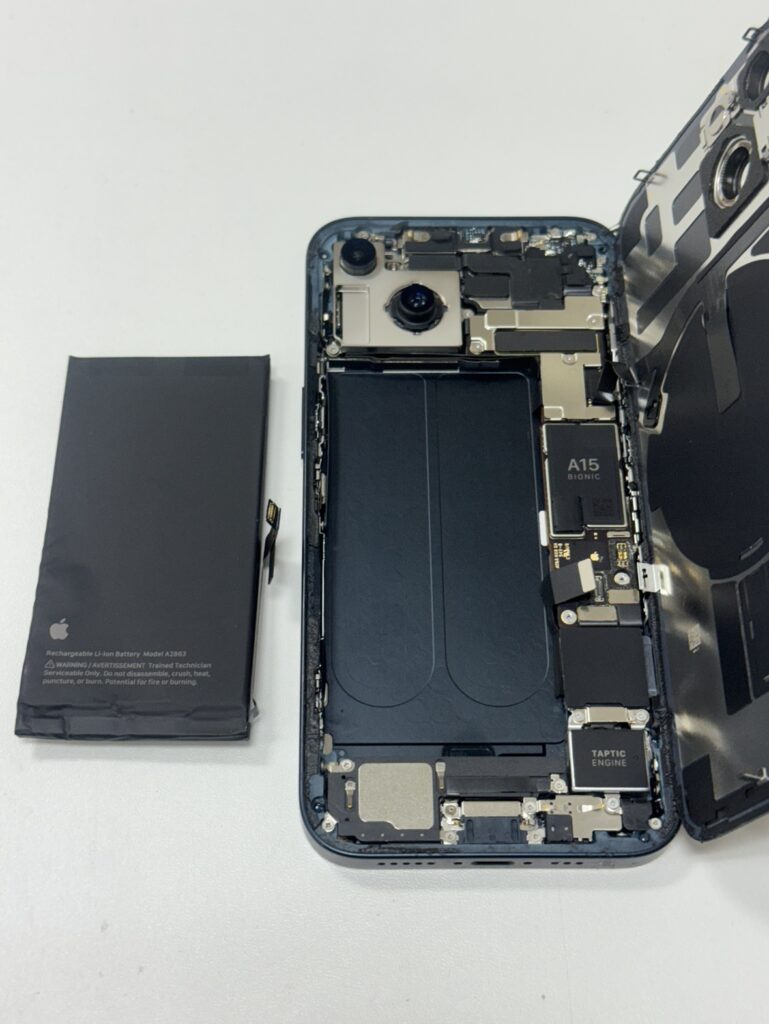 iPhone 14の内部から古い電池を外す様子。