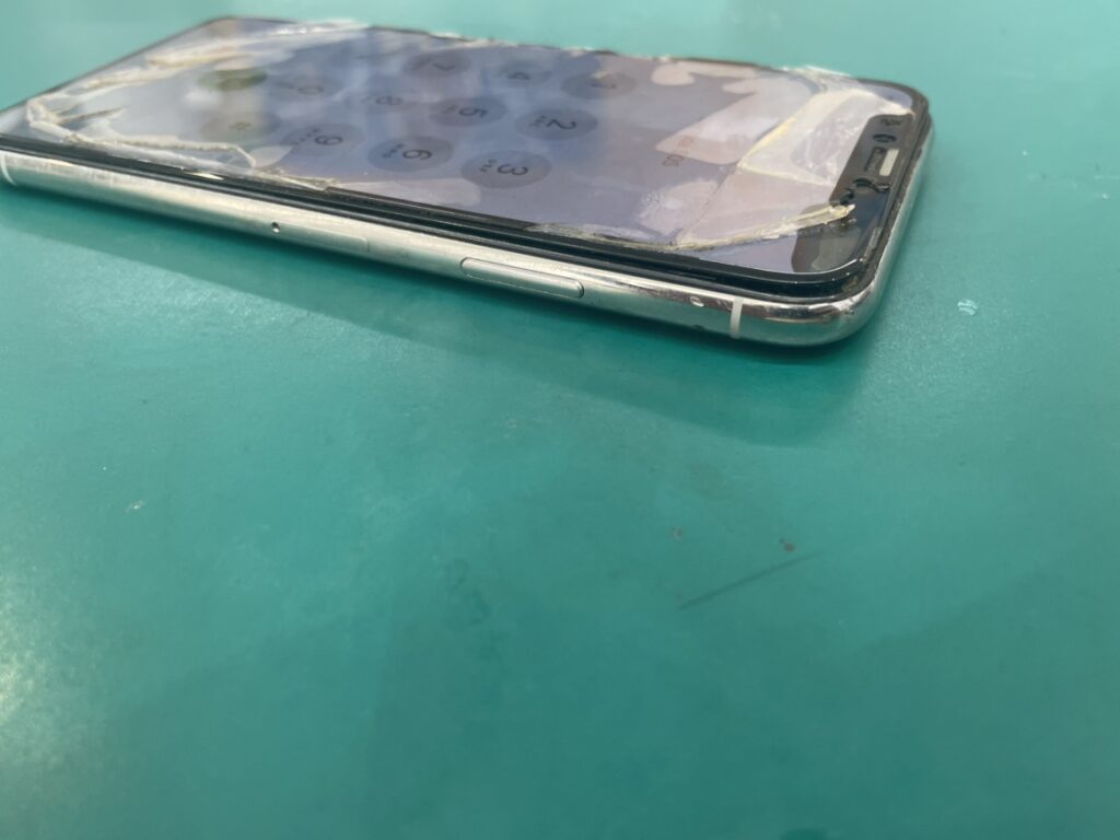 フェニックス横浜関内本店に持ち込まれたiPhoneX、バッテリー膨張により液晶画面が側面から激しく浮いている様子