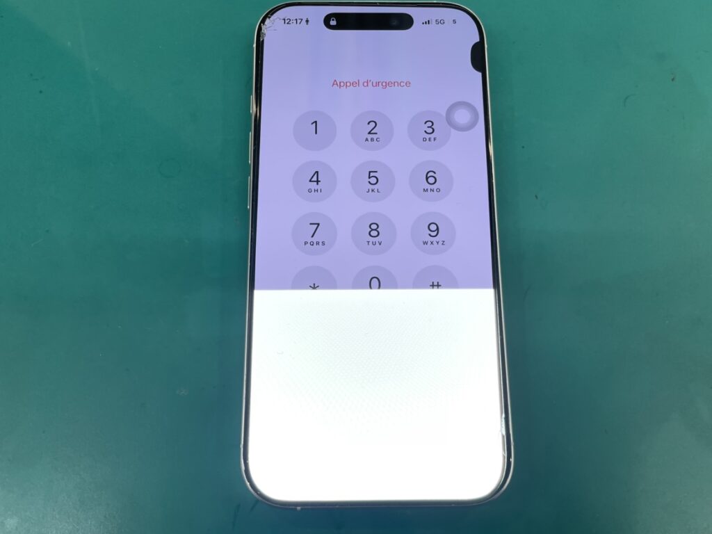 机にぶつけた衝撃で画面の下半分が激しく緑色に発光しているiPhone16Proのディスプレイ状態