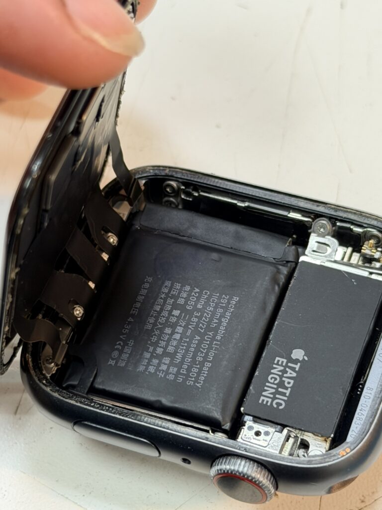Apple Watch 4の画面を慎重に開き、内部の劣化したバッテリーを取り外す様子。