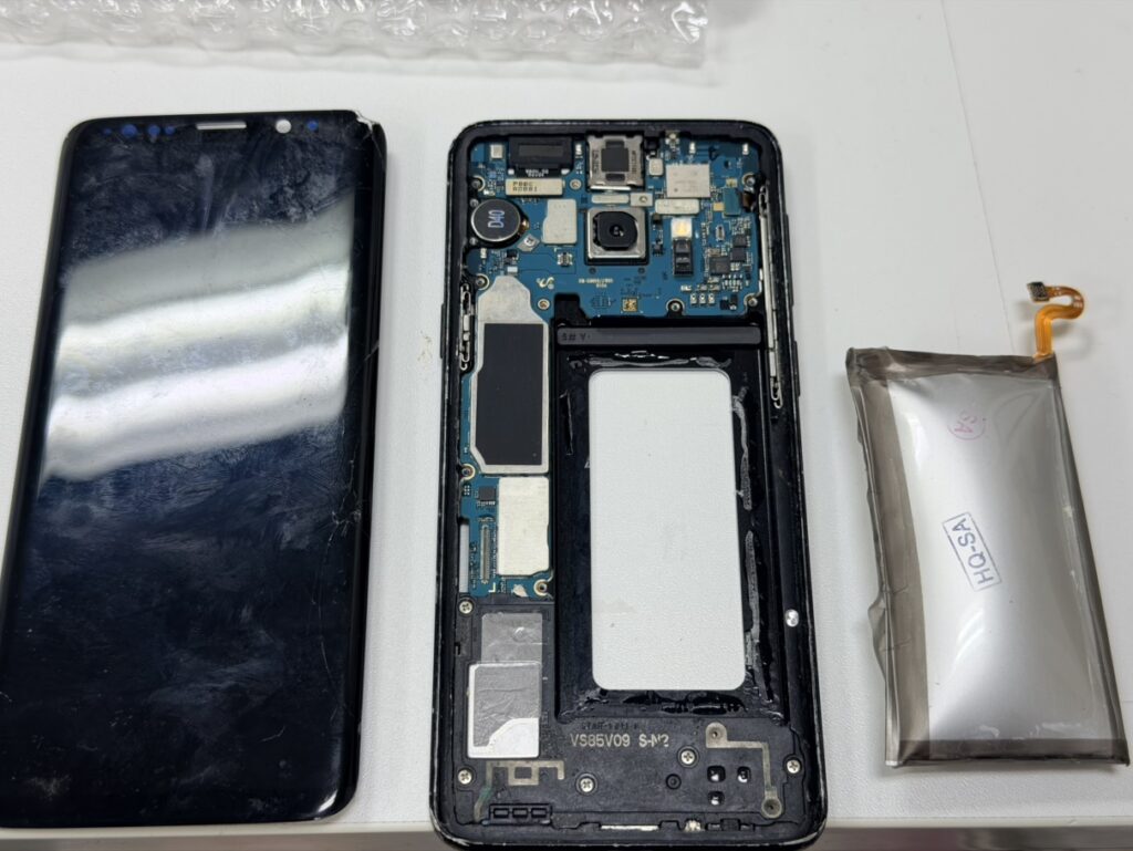 Galaxy S9の内部から、膨らんだ危険なバッテリーを慎重に取り外す様子。