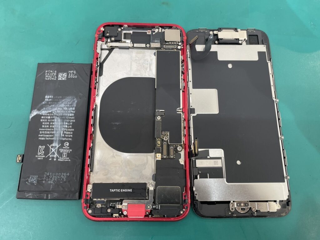 iPhoneSE2の内部を分解し古いバッテリーを専用工具で取り外している様子