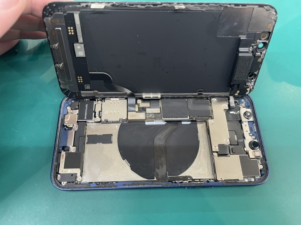 フェニックス横浜関内本店の技術者がiPhone12miniの画面を安全に開き、古いバッテリーを慎重に外している様子
