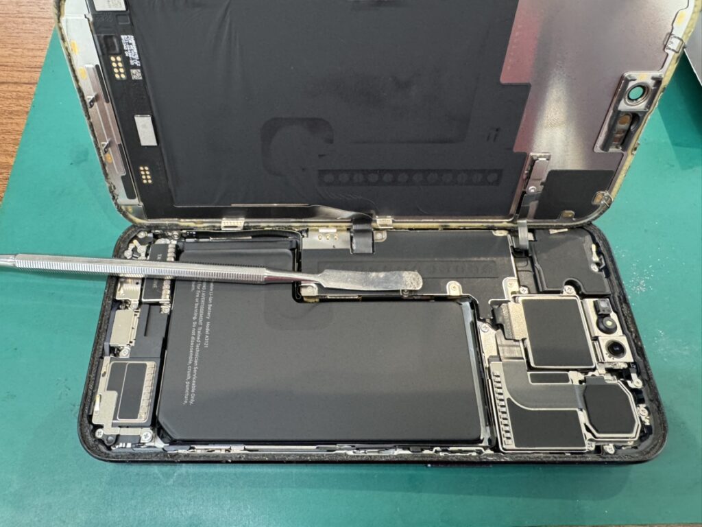 修理工房さいか屋横須賀店でiPhone 15 Pro Maxの電池を取り外し中