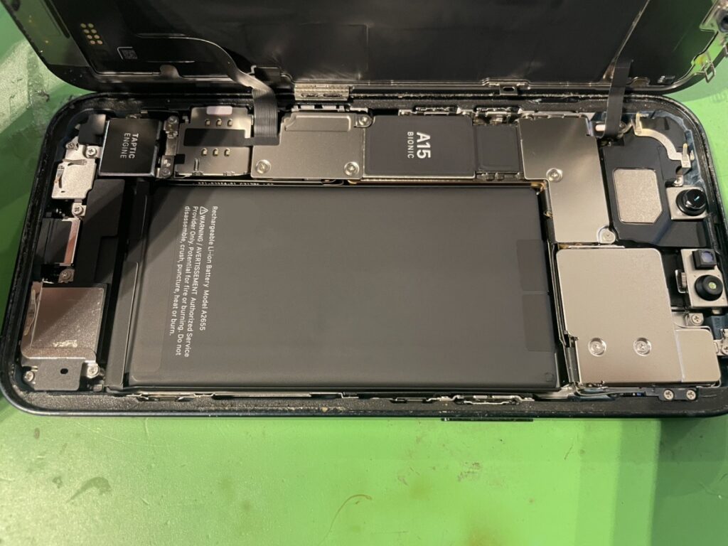 iPhone13の画面を開き、内部の水濡れ反応(水没シール)が正常であることを確認しながらバッテリーを分解する様子