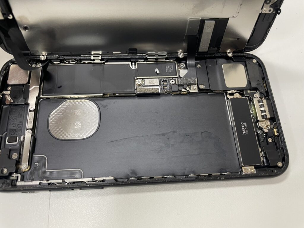 フェニックス横浜関内本店の技術者が、iPhoneSE2の画面を開き、劣化したバッテリーを安全に取り外している様子