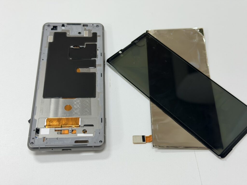 Xperia 5 IIIの背面から慎重に分解し、画面パーツの交換作業を行っている様子。